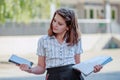 Girl schoolgirl compares the tablet and textbooks. The child is holding a tablet and books. The student has an idea. The girl in Royalty Free Stock Photo