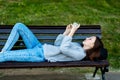 Girl schoolgirl. In summer, he lies on a bench in city. In the hands of holding a smartphone, watching a video. Concept Royalty Free Stock Photo