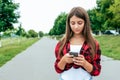 Girl schoolgirl 13-16 years old stands in the city in the hand in the summer in city. Online chat application in social Royalty Free Stock Photo