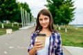 A girl schoolgirl, 13-16 years old, stands summer in city in hand cup with a coffee tea drink. Free space for text