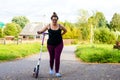 girl with a scooter climbs the hill on foot and holds her sore back with her hand Royalty Free Stock Photo