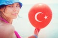 Girl on sea with balloon of Turkish flag in hand, Turkey. Tropical resort beach vacation