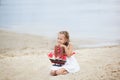 Girl on the sea with a ship. Close-up portrait of the girl`s face. little girl wait boat with scarlet sail. Girl on the beach in a Royalty Free Stock Photo