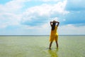 Girl in sea water. Sea landscape. Sea bank and cloudy sky. Green water surface, forest on horizont line and blue sky with clouds. Royalty Free Stock Photo