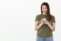 Girl searching album of singer in app wearing wired earphones and typing in smartphone looking casually with pleased