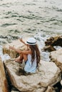 Girl seashore stone is wet  spray waves Royalty Free Stock Photo