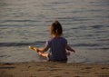 Girl in a seaman suit plays with kids' shovel on a beach