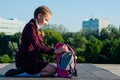 girl of the senior classes, takes out textbooks from a pink backpack in the open air