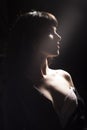 Girl with sensual face, naked shoulder, decollete in dark room. Royalty Free Stock Photo