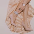 Girl sensual legs in shoes on beige silk textile background. .Fashion Jewelry Accessory watch and rings. Date, luxary look