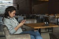 A girl with a serious expression sits alone in a cafe with a phone in her hands. Close-up. Horizontal side view Royalty Free Stock Photo