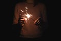 Girl sets fire to sparkler, dark background Royalty Free Stock Photo