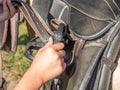 Girl setting plastic stirrups on back of leather saddle