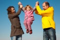 Girl shakes on hands at parents against sky Royalty Free Stock Photo