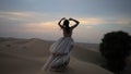 A girl in a shiny dress dances barefoot in the sand