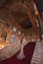 A girl in a shiny dress standing on the steps of a luxurious historical palace staircase.