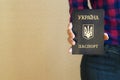 A girl in a shirt and jeans holds in his hand a Ukrainian passport