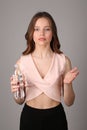 Girl in shirt posing with bottle of water. Close up. Gray background Royalty Free Stock Photo