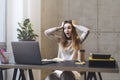 Girl shocked by picture, video, message on screen of laptop. Young manager sitting at workplace trying to meet project deadline.