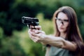 Girl shooting instructor with a gun in his hand aiming at the target