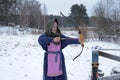 A girl shoots in the winter from a bow at the festival of medieval Vikings