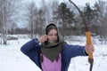 A girl shoots in the winter from a bow at the festival of medieval Vikings