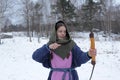 A girl shoots in the winter from a bow at the festival of medieval Vikings