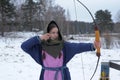 A girl shoots in the winter from a bow at the festival of medieval Vikings