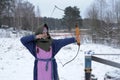 A girl shoots in the winter from a bow at the festival of medieval Vikings