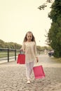 Girl shopping on calm face carries bags, urban background. Kid girl with long hair fond of shopping. Fashionista girl