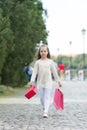 Girl shopping on calm face carries shopping bags, urban background. Kid girl with long hair fond of shopping. Shopping Royalty Free Stock Photo