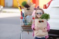 Girl with a shopping cart full of groceries near the car Royalty Free Stock Photo