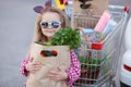 Girl with a shopping cart full of groceries near the car Royalty Free Stock Photo