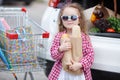 Girl with a shopping cart full of groceries near the car Royalty Free Stock Photo