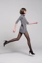 Girl in a short dress, black tights and shoes jumps in the studio on a white background Royalty Free Stock Photo