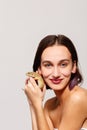 A girl with short hair and bare shoulders holding an iguana gecko in hand and pressing her to face and smiling .