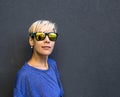 A girl with short hair stands against a dark gray wall Royalty Free Stock Photo