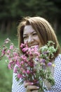 A girl with a short haircut laughs and hides behind flowers. A close portrait of a young beautiful woman in a meadow with lilac