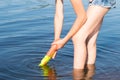 Girl in shorts stands in the river and fills the water pistol with water, close-up