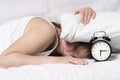 Girl shoved her head under pillow when alarm clock rang in the morning. Early to get up on the alarm clock Royalty Free Stock Photo