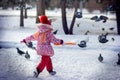 The girl in the park runs disperses pigeons in the winter Royalty Free Stock Photo