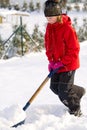 Girl shoveling snow on home drive way. Beautiful snowy garden or front yard. Teenager removing snow with a shovel in the Royalty Free Stock Photo