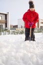 Girl shoveling snow on home drive way. Beautiful snowy garden or front yard. Teenager removing snow with a shovel in the Royalty Free Stock Photo