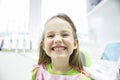 Girl showing her healthy milk teeth at dental office