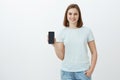 Girl showing new phone parents bought for new school term. Delighted and pleased charming young woman showing smartphone