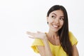 Girl showing product changed her life. Portrait of joyful pleased cute european female with dark hair in trendy yellow t