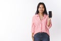 Girl showing smartphone she suggests buy. Delighted happy attractive young polynesian female in striped pink blouse