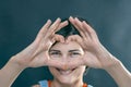 The girl shows a heart folded from her fingers and smiles