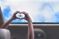 Girl shows her hands in a form of heart on the airplane in open hatch of a vehicle.