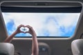 Girl shows her hands in a form of heart on the airplane in open hatch of a vehicle.